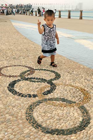 A child looks at a collage of Olympic rings in Olympic co-host city Qingdao of east China's Shandong Province, July 28, 2008. Beijing Olympic sailing events will to be held in Qingdao from Aug. 9th to 23rd and the Paralympic sailing events from September 8th to 13th. 