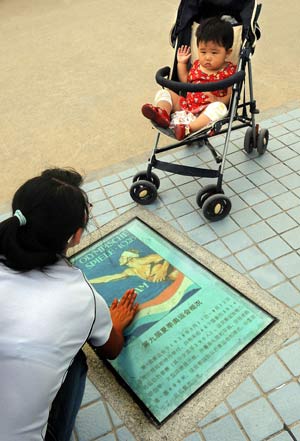 A local resident teaches her child with a lamp box embeded with Olympic knowledges in Olympic co-host city Qingdao of east China's Shandong Province, July 27, 2008.