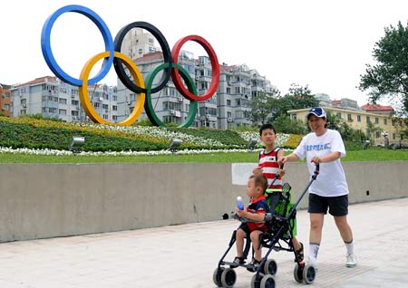 Local residents pass by the Olympic rings sculpture in Olympic co-host city Qingdao of east China's Shandong Province, July 27, 2008. Beijing Olympic sailing events will to be held in Qingdao from August 9th to 23rd and the Paralympic sailing events from September 8th to 13th.(Xinhua/Wang Song)