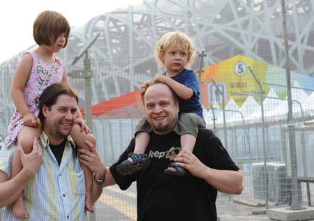 Two foreign tourists carry their children while posing in front of the National Stadium, or the Bird's Nest in Beijing July 26, 2008. 