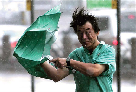 A man tries to stop his umbrella from flying away as Typhoon Fung Wong hit Taipei yesterday. It packed wind gusts of up to 190 kph and forced businesses and markets to close. 