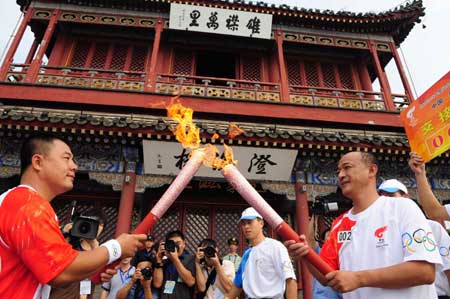 Torchbearer Nie Ruiping (R) lights the troch for the next torchbearer Liu Zhonghua during the 2008 Beijing Olympic Games torch relay in Qinhuangdao, a co-host city of Beijing 2008 Olympic Games in north China's Hebei Province, July 30, 2008.