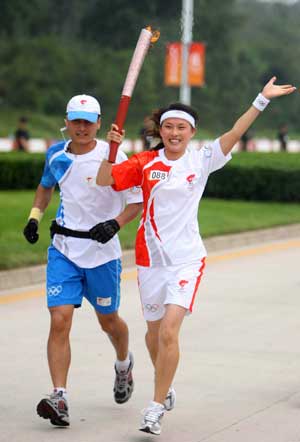 Torchbearer Zang Shasha runs with the torch during the 2008 Beijing Olympic Games torch relay in Qinhuangdao, a co-host city of Beijing 2008 Olympic Games in north China's Hebei Province, July 30, 2008.