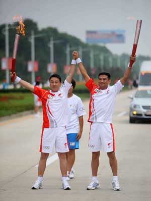 Torchbearer Hao Hongjiang(R) poses with the next torchbearer Zhao Yanbing during the 2008 Beijing Olympic Games torch relay in Qinhuangdao, a co-host city of Beijing 2008 Olympic Games in north China's Hebei Province, July 30, 2008. 