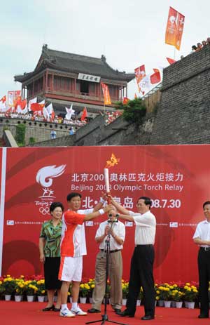 The first torchbearer Xi Enting (L) receives the torch during the 2008 Beijing Olympic Games torch relay in Qinhuangdao, a co-host city of Beijing 2008 Olympic Games in north China's Hebei Province, July 30, 2008.