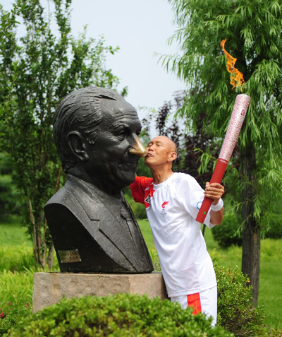 Torchbearer Ji Shaolin kisses statue of Juan Antonio Samaranch during the 2008 Beijing Olympic Games torch relay in Qinhuangdao, a co-host city of Beijing 2008 Olympic Games in north China's Hebei Province, July 30, 2008. 