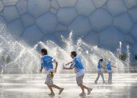 Volunteers play at the fountain in front of the National Natatorium bubbed as the "Water Cubic" in Beijing, China, July 29, 2008. The sky cleared after a rainfall in some areas of the capital Tuesday. 