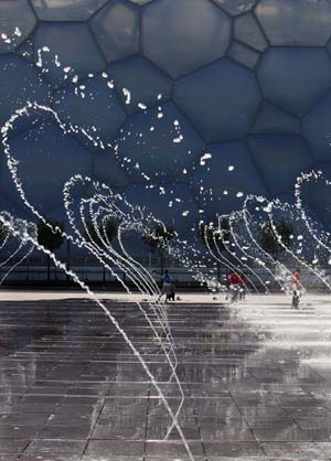Fountain water dance in front of the National Aquatics Center, nicknamed the "Water Cube", in Beijing, China, July 29, 2008. The sky cleared after a rainfall in some areas of the capital Tuesday.