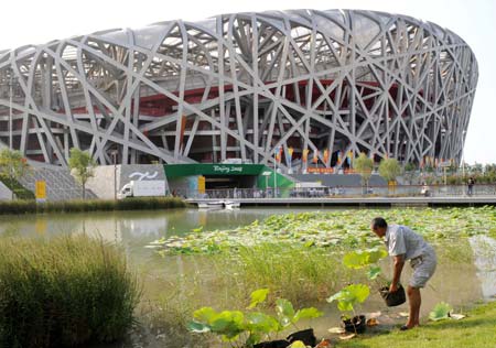 A worker arranges potted flower in front of the National Stadium, nicknamed the 