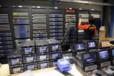 A staff member ajusts the facilities in the International Broadcast Center (IBC) in Beijing, China, July 29, 2008. It’s said that high definition signals will be first-ever used for TV relays for all 28 events of Beijing 2008 Olympic Games. BOB will produce live TV signals of 5,400 hours for right-holding broadcasters and it’s estimated that more than four billion viewers will enjoy the olympic competition through TV broadcasts in 2008. (Xinhua/Li Ziheng)