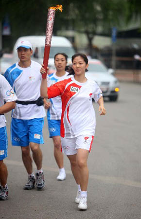 Torchbearer Niu Jianfeng holds up the torch during the Beijing 2008 Olympic Games torch relay in Tangshan, north China's Hebei Province, July 31, 2008.