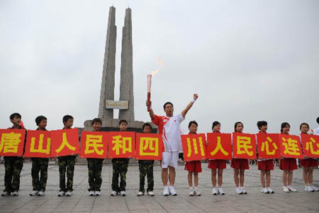 Torchbearer Song Zhiyong holds up the torch during the Beijing 2008 Olympic Games torch relay in Tangshan, north China's Hebei Province, July 31, 2008. 