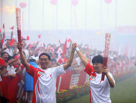 Torchbearer Qian Hong (R) poses with the next torchbearer Liu Zhijun during the Beijing 2008 Olympic Games torch relay in Tangshan, north China's Hebei Province, July 31, 2008.