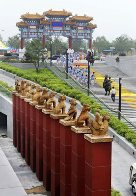 Volunteers walk past the north gate of the underground square in the Olympic Green in Beijing July 28, 2008. Located to the north of the Bird's Nest, the underground square gives a presentation of Chinese culture.
