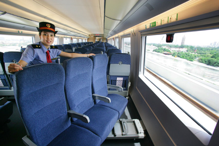 A stewardess displays the rotating chairs in a Beijing-Tianjin high-speed train on its test run July 17, 2008. The new 350 kph train shortens the journey between the two cities to just 30 minutes. The Beijing-Tianjin high-speed railway will open on August 1, 2008. 
