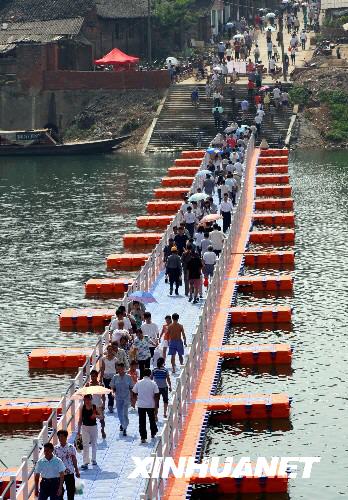 Citizens pass over a colorful floating bridge on the Xiaoshui River in Yongzhou, Hunan Province on Wednesday, July 30, 2008.