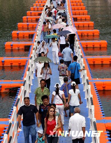 Citizens pass over a colorful floating bridge on the Xiaoshui River in Yongzhou, Hunan Province on Wednesday, July 30, 2008.