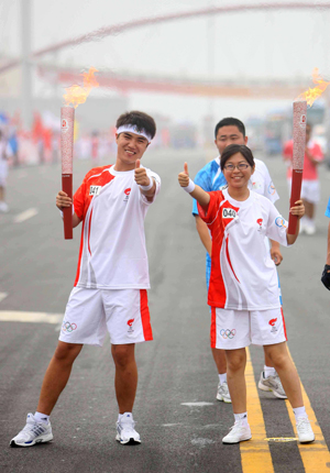 Torchbearer You Lihong (R) poses with the next torchbearer Wei Hong during the 2008 Beijing Olympic Games torch relay in north China's Olympics co-host city Tianjin, August 1, 2008. [Xinhua]