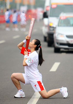 Torchbearer Wang Ju kisses the torch during the 2008 Beijing Olympic Games torch relay in north China's Olympics co-host city Tianjin, August 1, 2008. [Xinhua]