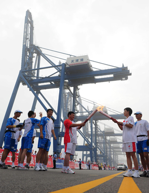 Torchbearer Chang Ying (2nd R) lights the torch for the next torchbearer Zhao Zhiming during the 2008 Beijing Olympic Games torch relay in north China's Olympics co-host city Tianjin, August 1, 2008. [Xinhua]