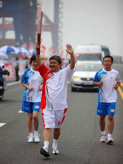 Torchbearer Liu Huan (C) runs with the torch during the 2008 Beijing Olympic Games torch relay in east China's Tianjin Municipality, August 1, 2008. [Xinhua]