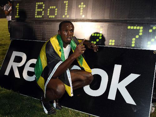Usain Bolt of Jamaica crouches beside the new men&apos;s 100m world record he made at the Reebok Grand Prix meeting at Icahn Stadium in New York on Saturday, May 31, 2008. [Xinhua]