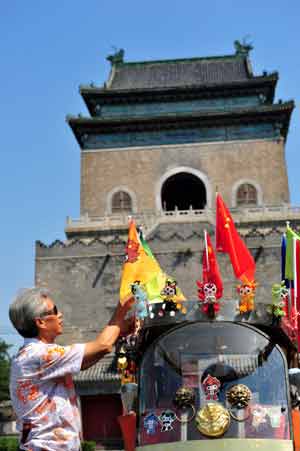 A trishaw dirver decorates his three-wheel cart in front of the Bell Tower in Beijing, capital of China, Aug. 3, 2008. 