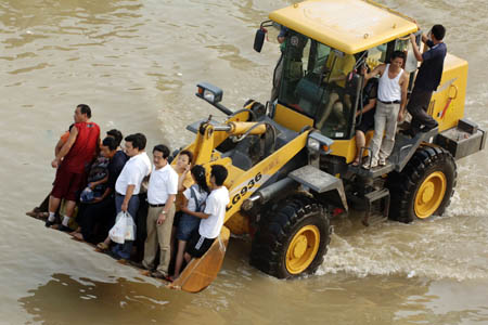 Local residents are evacuated from the flooded areas by a shovel loader in Quanjiao, east China's Anhui Province, Aug. 3, 2008. Torrential rains since July 31 have resulted in the rising of water levels, which exceeded warning levels in some sections of Chuhe River, Deshenghe River and Xingxihe River in the region. The flood has forced relocation of 76,361 people in Anhui, according to the provincial flood control and drought relief headquarters. (Xinhua/Li Jian)