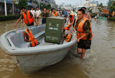 Soldiers of the People's Liberation Army (PLA) help local residents transfer daily goods on the flooded street in Quanjiao, east China's Anhui Province, Aug. 3, 2008. Torrential rains since July 31 have resulted in the rising of water levels, which exceeded warning levels in some sections of Chuhe River, Deshenghe River and Xingxihe River in the region. The flood has forced relocation of 76,361 people in Anhui, according to the provincial flood control and drought relief headquarters. (Xinhua/Li Jian) 