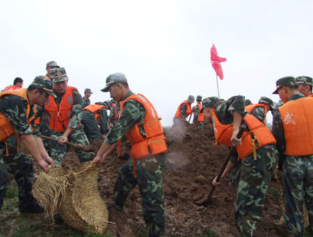 Armed police fill sand bags for the enforcement of a river bank in Chuzhou City in central China's Anhui province on August 2, 2008. Caused by tropical storm Fung Wong, heavy rainfalls triggered floods in large areas of Chuzhou City on August 1 and August 2, demaging roads, bridges, river banks and power facilities.