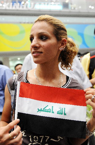 An Iraqi athlete walks out of the Beijing Capital International Airport at the midnight of August 4, with an iraqi national flag in her hand. [Xinhua]