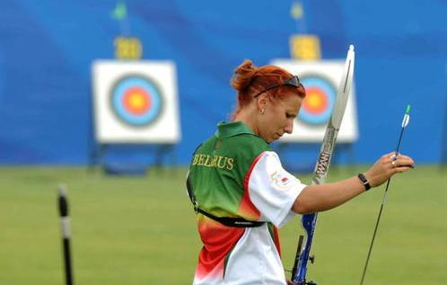 A Belarus archer is pulling an arrow from her bag, ready to aim. 