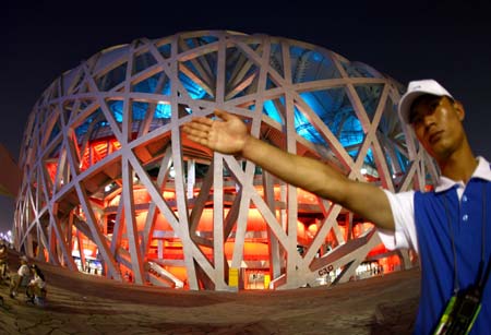 A volunteer guides spectators outside the National Stadium, nicknamed the Bird&apos;s Nest, in Beijing, China, Aug. 5, 2008. A dress rehearsal of the opening ceremony of Beijing 2008 Olympic Games was held on Tuesday. (Xinhua/Chen Jianli) 