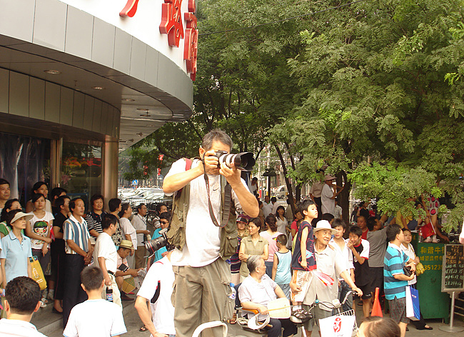 A crowd gathered to watch the torch relay in Xuanwu District. A photographer has to use a ladder to reach a better position to take pictures. [China.org.cn] 