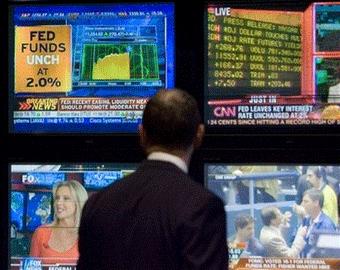 Television screens on the floor of the New York Stock Exchange announce the Federal Reserve interest rate decision. 