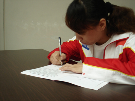 A member of the Chinese Wushu Delegation signs an anti-doping oath. 