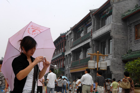 A young lady views photos she just took on the newly-renovated Qianmen Street in central Beijing, China, Aug. 7, 2008.[Jin Liangkuai/Xinhua]