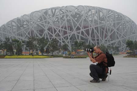 A photographer takes photos in front of National Stadium, nicknamed Bird's Nest, in Beijing, China, at about 8 a.m. on Aug 8, 2008, 12-hour countdown to the opening ceremony of the Olympics. The opening ceremony of the Beijing 2008 Olympic Games will be held in the National Stadium at 8 p.m. on Aug 8. [Xinhua] 