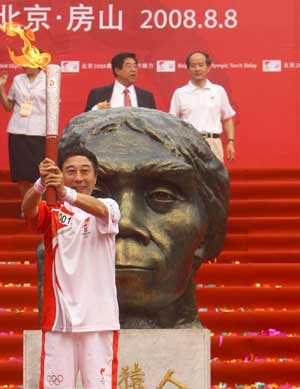 The first torchbearer Feng Gong holds up the torch at the start of the last-day of Beijing Olympic Games torch relay in Zhoukoudian of Beijing, China, Aug. 8, 2008. The Olympic torch started its final-hours relay on Friday morning at Zhoukoudian, an UNESCO heritage site in southwestern Beijing suburb which has yielded many archaeological discoveries. 
