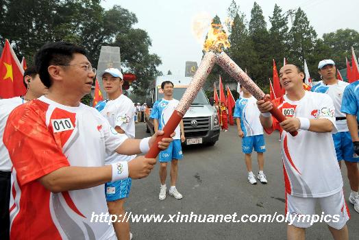 Torchbearer Zhang Hongxin (R) passes the flame to the next torchbearer Qi Hong (L) during the last-day of Beijing Olympic Games torch relay in Beijing, China, Aug. 8, 2008. (Xinhua/Liu Lihang)