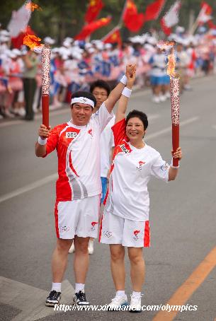 Torchbearer Li Guihua (R) poses with next torchbearer Liu Changming during the last-day of Beijing Olympic Games torch relay in Beijing, China, Aug. 8, 2008.
