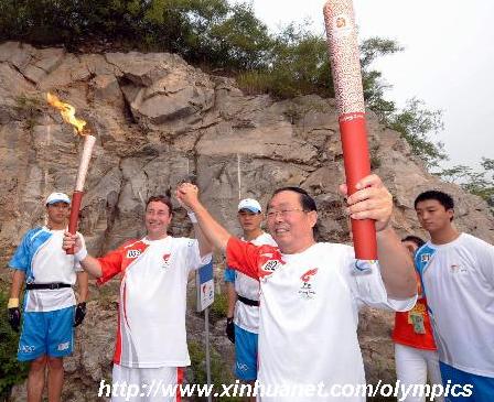 torchbearer Tian Xiong (2nd R) poses with next torchbearer Achim Steiner (2nd L) during the last-day of Beijing Olympic Games torch relay in Beijing, China, Aug. 8, 2008. (Xinhua/Xing Guangli)
