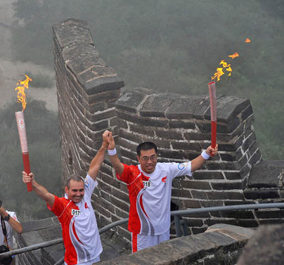 Torchbearer Colin Giles (L) poses with the next torchbearer Wang Ning during the Beijing 2008 Olympic Games torch relay in Beijing, China, Aug. 7, 2008. (Xinhua/Li Yi) 