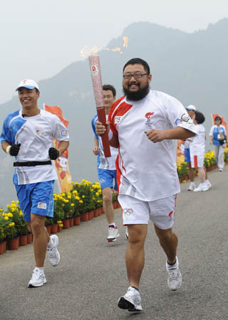 Torchbearer Guan Chenghua runs with the torch during the Beijing 2008 Olympic Games torch relay in Beijing, China, Aug. 7, 2008. (Xinhua/Qi Heng)