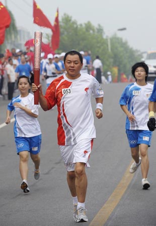 Torchbearer Wang Pingjiu (C) runs with the torch during the Beijing 2008 Olympic Games torch relay in Beijing, China, Aug. 7, 2008. (Xinhua/Qi Heng) 