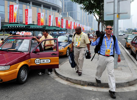 Two journalists arrive by taxi at Main Press Center near the National Stadium, known as the Bird's Nest, in Beijing, China, at about 3:00 p.m. on Aug. 8, 2008, 5-hour countdown to the opening ceremony of the Olympics. The opening ceremony of the Beijing 2008 Olympic Games will be held in the National Stadium at 8:00 p.m. on Aug. 8. (Xinhua/Li Ziheng)
