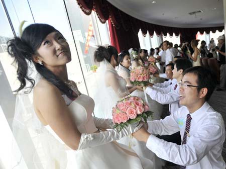 Chinese brides receive the bouquet of flowers from their grooms during a mass wedding ceremony in Wuhan, central China's Hubei province on 08 August 2008. 