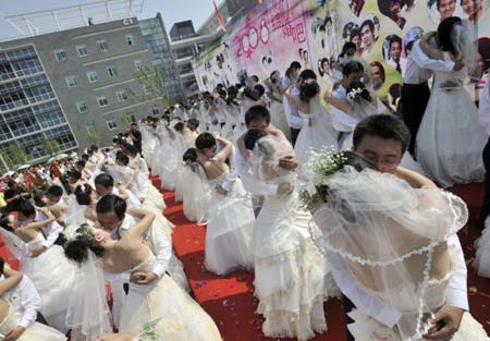 Chinese couples kiss during a mass wedding ceremony in Wuhan, central China's Hubei province on 08 August 2008.