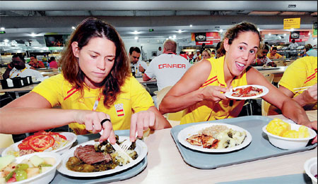 Athletes take supper at the dining hall in the Olympic village. File photo
