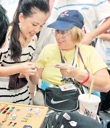 American Janet Grissom exchanges an Olympic pin with a local collector near the Olympic village yesterday. [China Daily]